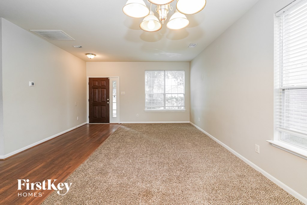 A spacious room with a carpeted floor and a chandelier hanging from the ceiling.