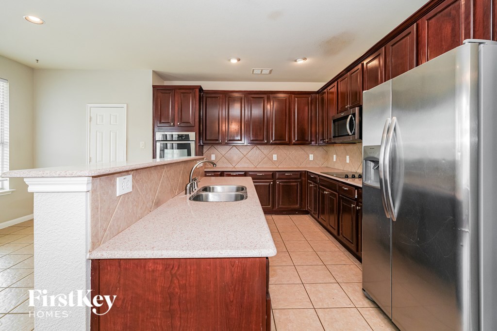 A kitchen with wooden cabinets and a stainless steel refrigerator.