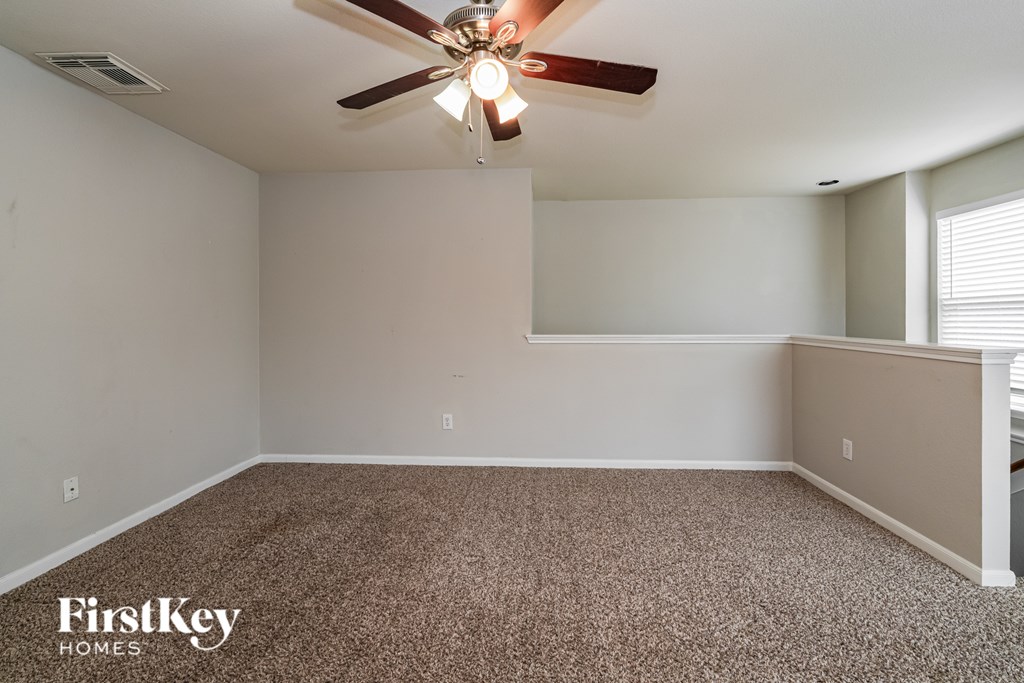 A room with a ceiling fan and carpeted floor.