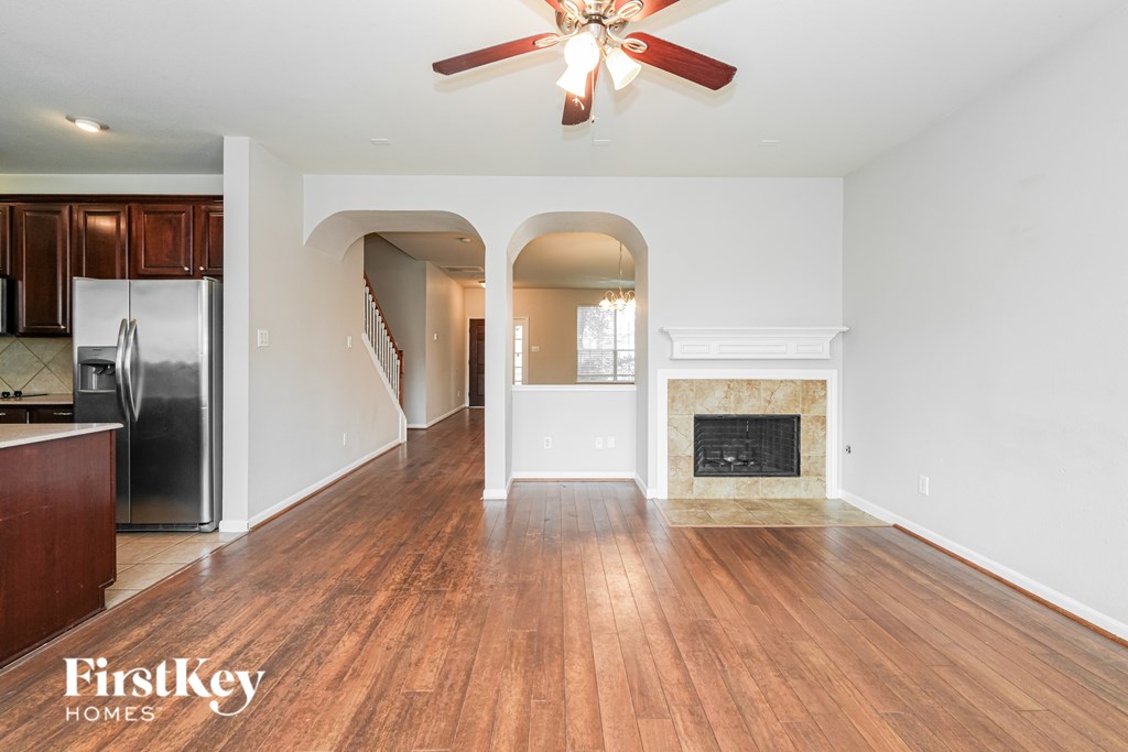 A spacious living room with wood flooring and a fireplace.