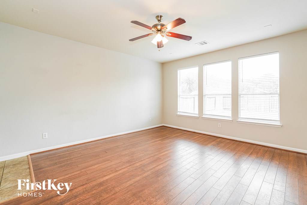 A room with a ceiling fan and wooden flooring.