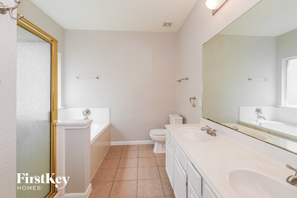 A bathroom with a toilet, sink, and mirror.