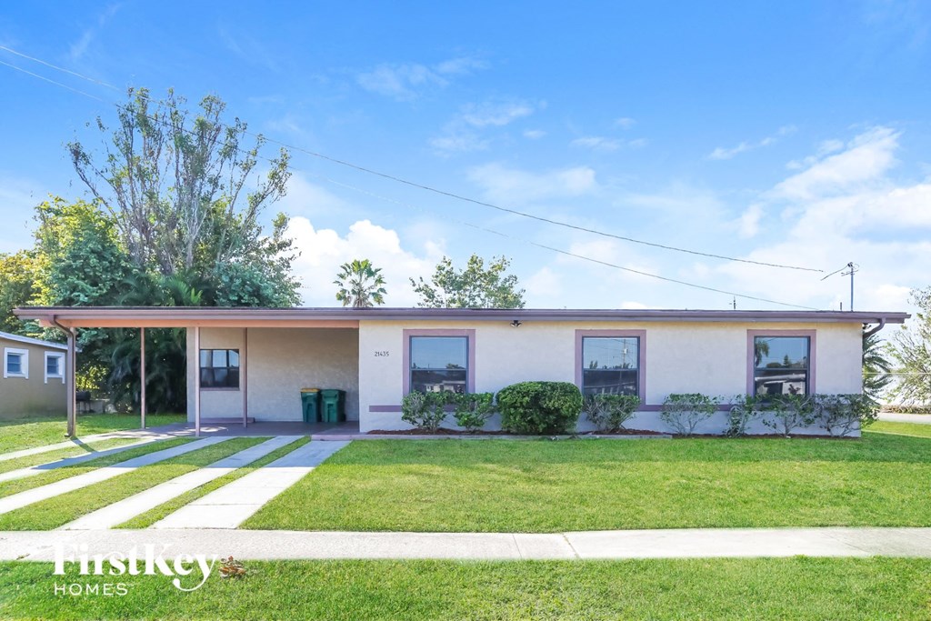 a small white house with a lawn and a driveway