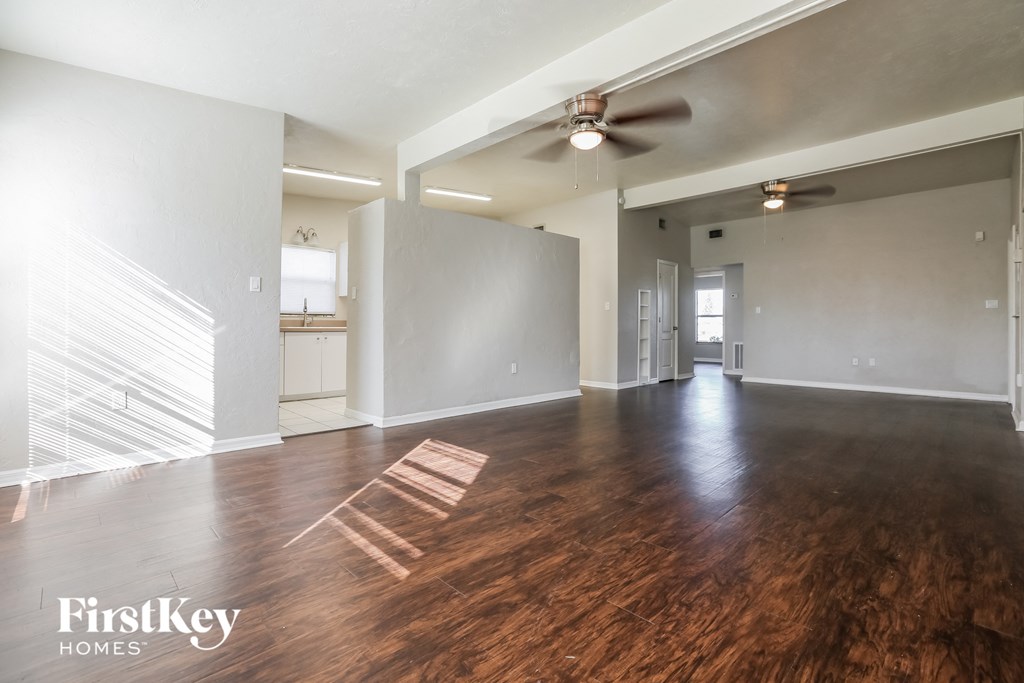 an empty living room with wood flooring and a ceiling fan