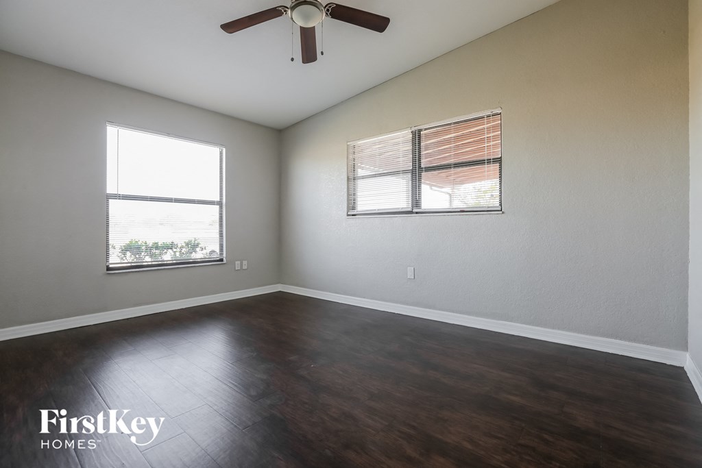 an empty living room with wood floors and a ceiling fan