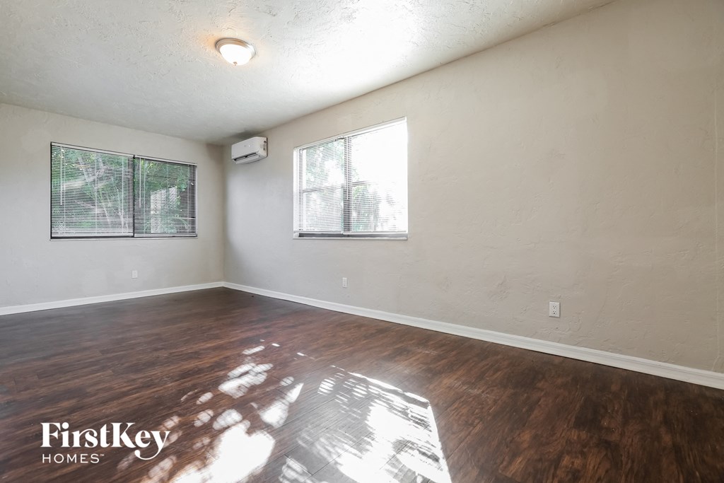 the living room of an empty house with wood flooring and a window