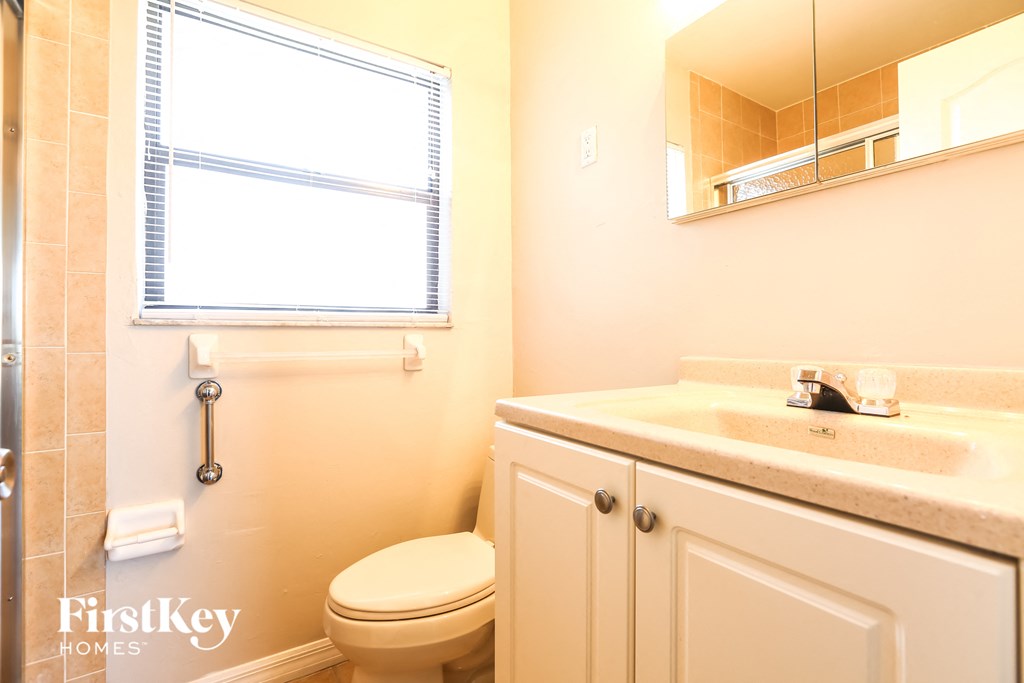 a bathroom with a toilet and a sink and a window