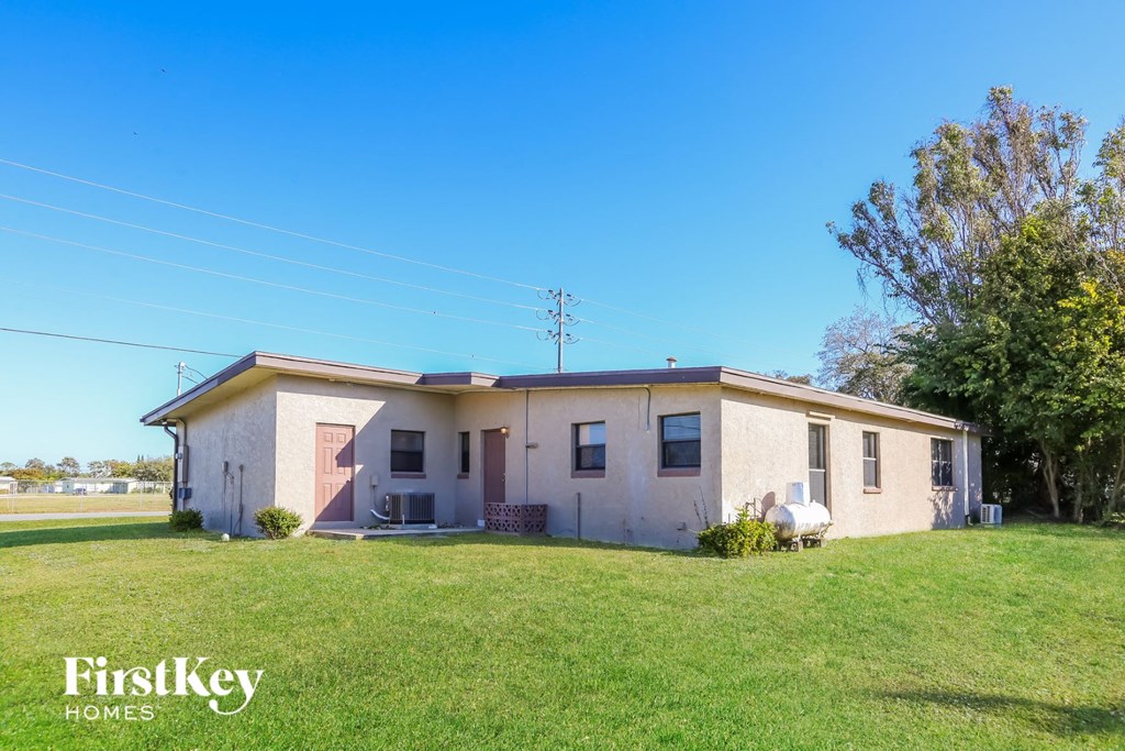 a small white house with a green lawn and a blue sky