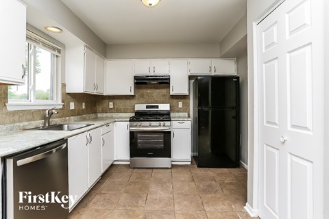 A kitchen with white cabinets and a black refrigerator.