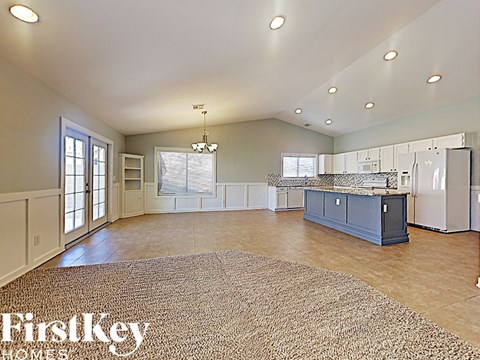 A spacious kitchen and living room with a rug on the floor.