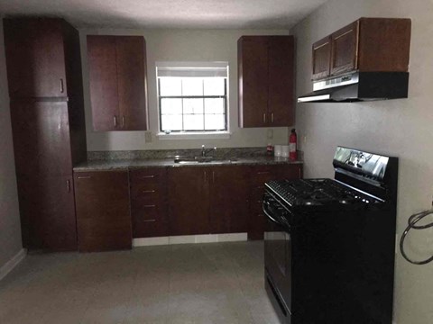 A kitchen with dark wood cabinets and a black stove top oven.