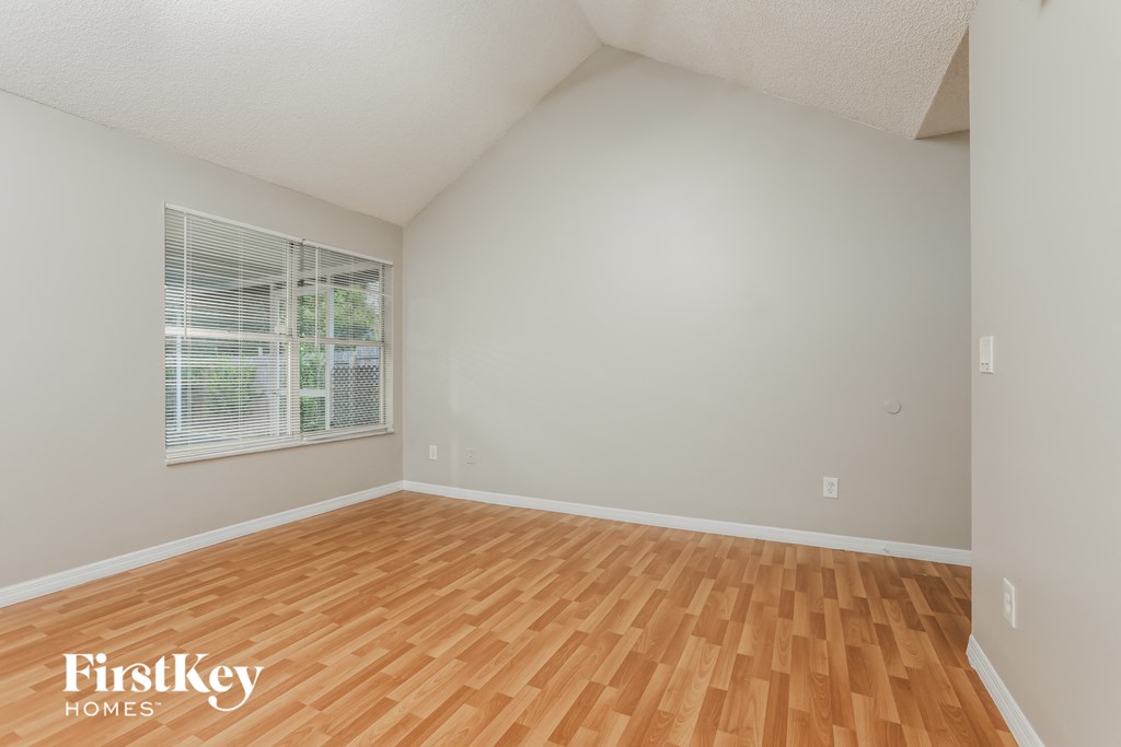 the spacious living room with hardwood flooring and a large window