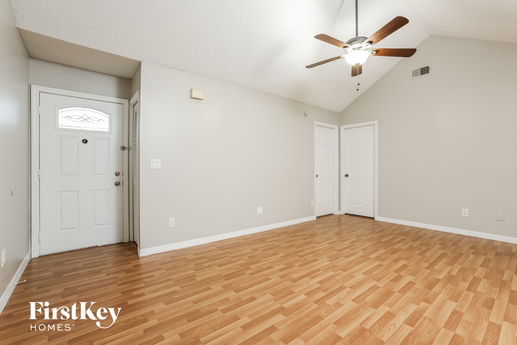 the spacious living room with hardwood flooring and a ceiling fan