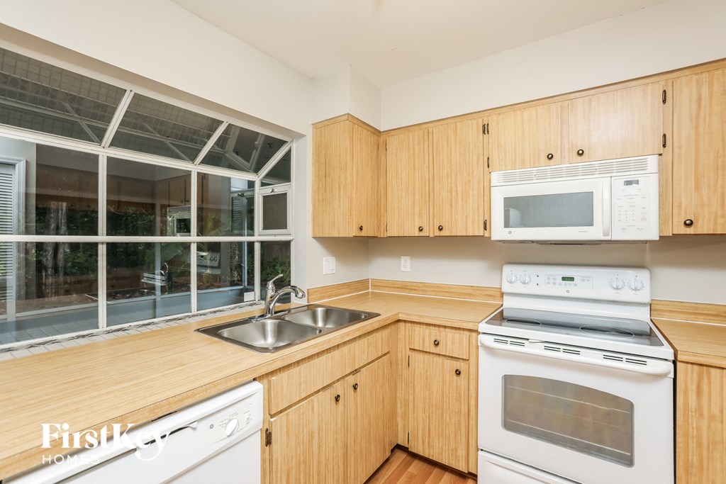 a kitchen with wooden cabinets and white appliances and a window