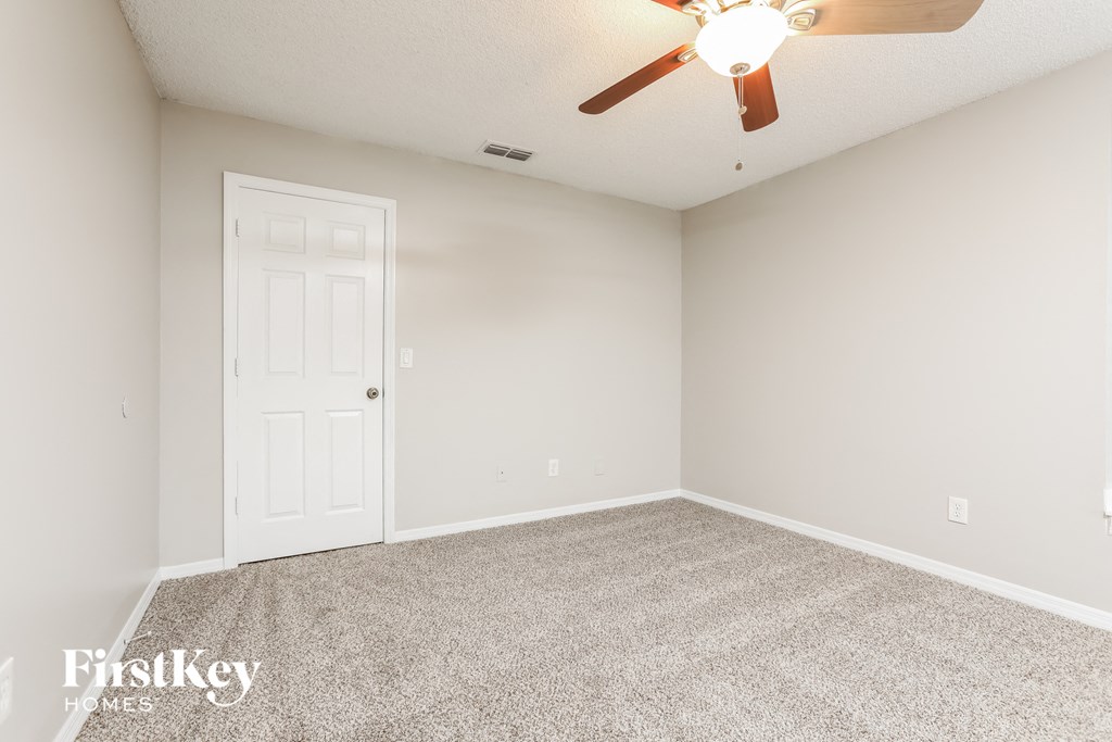 an empty room with a ceiling fan and a white door