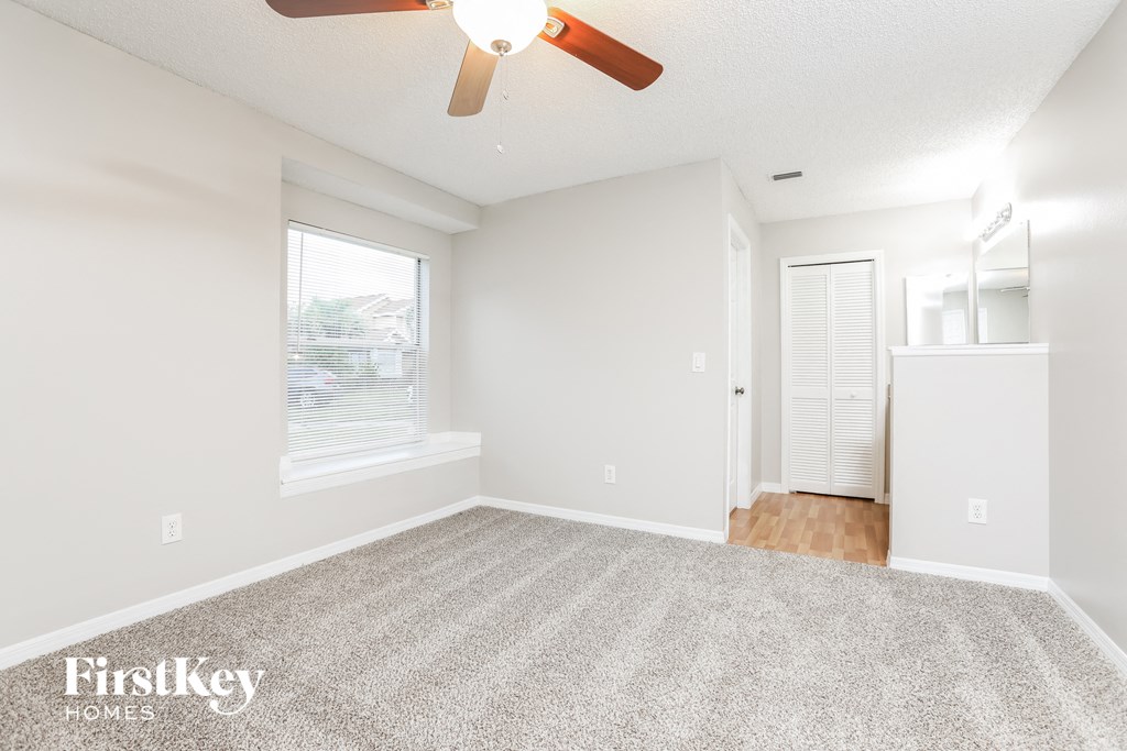 a spacious living room with carpet and a ceiling fan