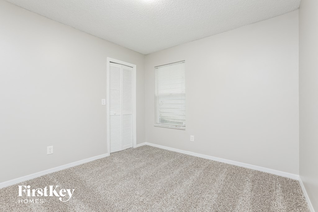 a spacious living room with carpet and white walls