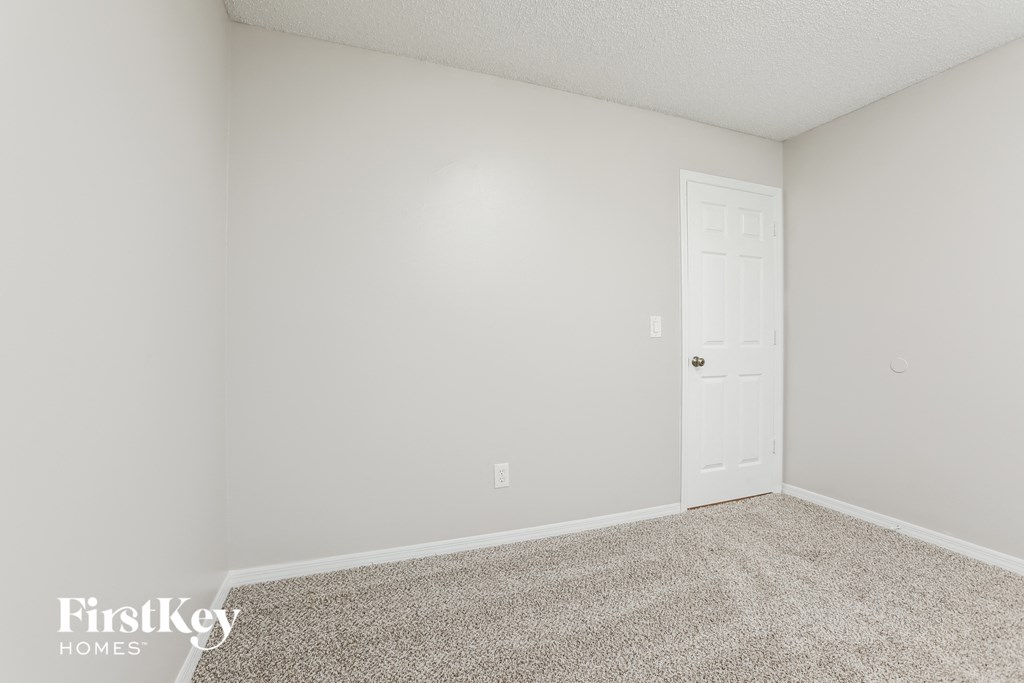 a bedroom with white walls and carpet and a door