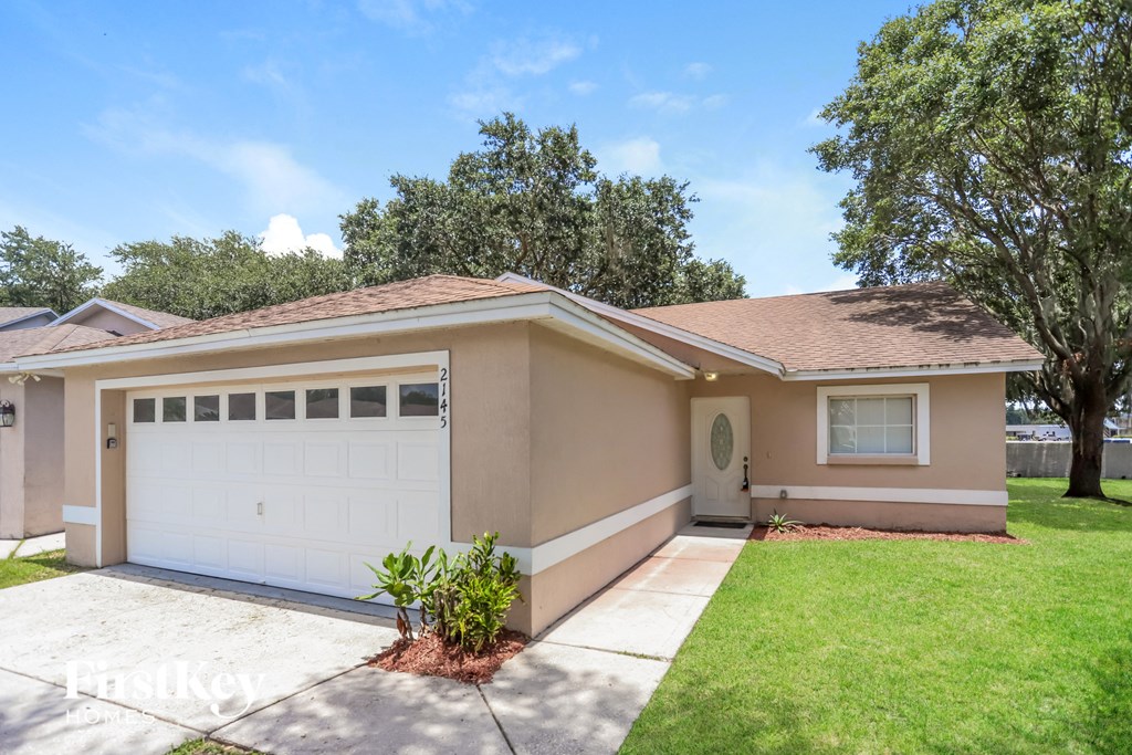 a beige house with a white garage door and a lawn