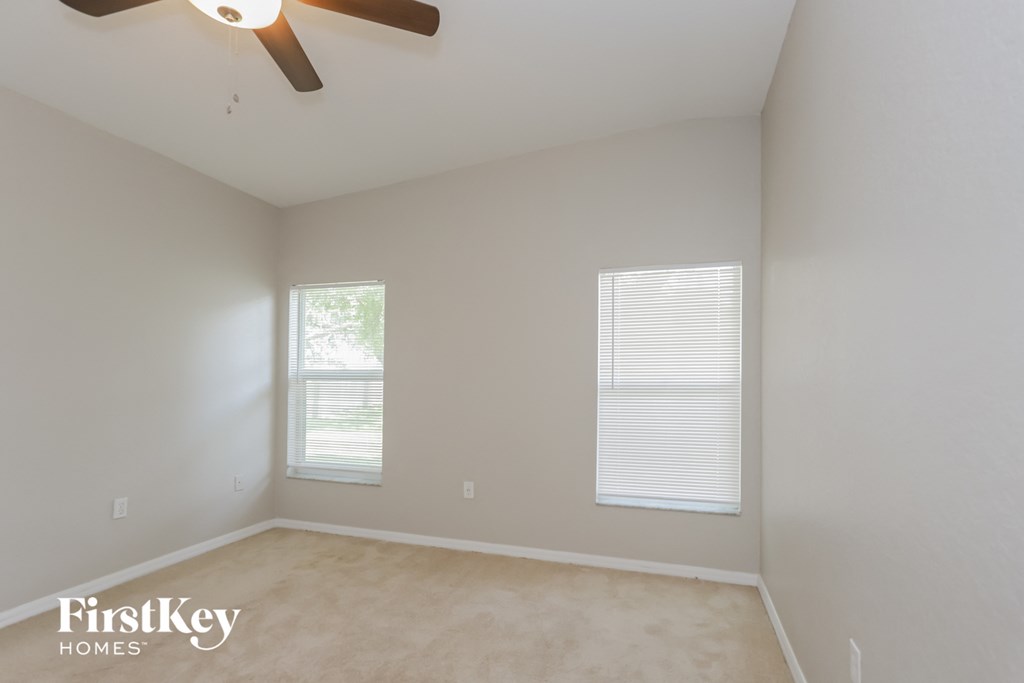 a empty room with a ceiling fan and two windows