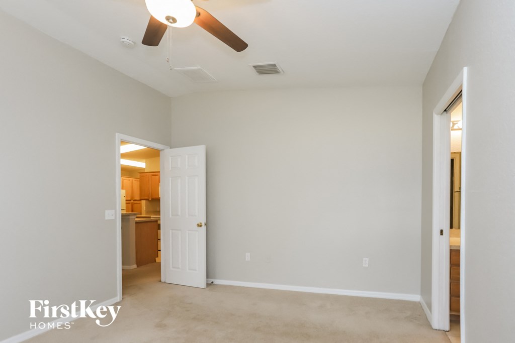 a living room with a ceiling fan and a door to a kitchen