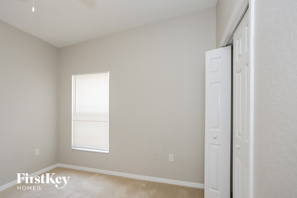 a bedroom with a closet and a window and a white door