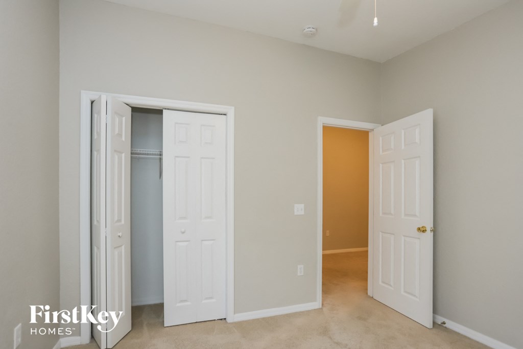 a bedroom with two closets and two doors and a carpeted floor