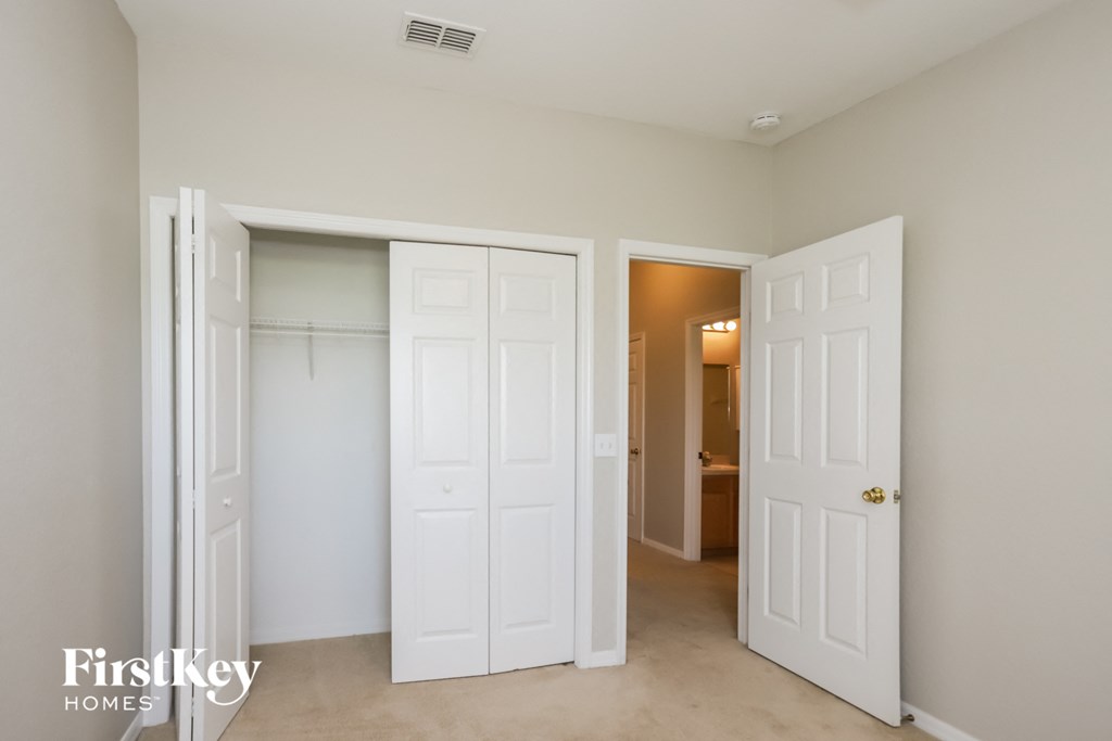 a bedroom with two closets and two doors and a hallway to a bathroom