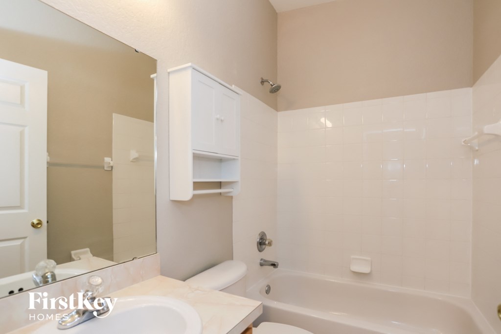 a white bathroom with a tub and a sink and a mirror
