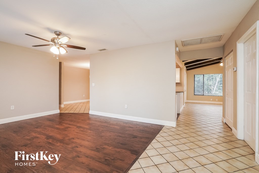 an empty living room with a ceiling fan and wood floors