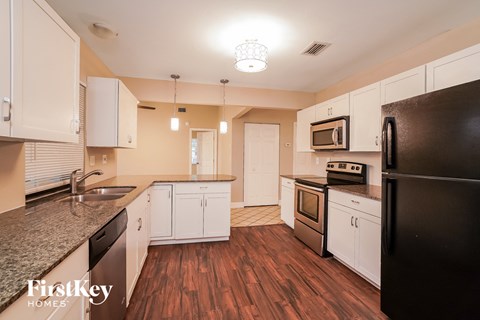 a kitchen with white cabinets and black appliances and a wood floor