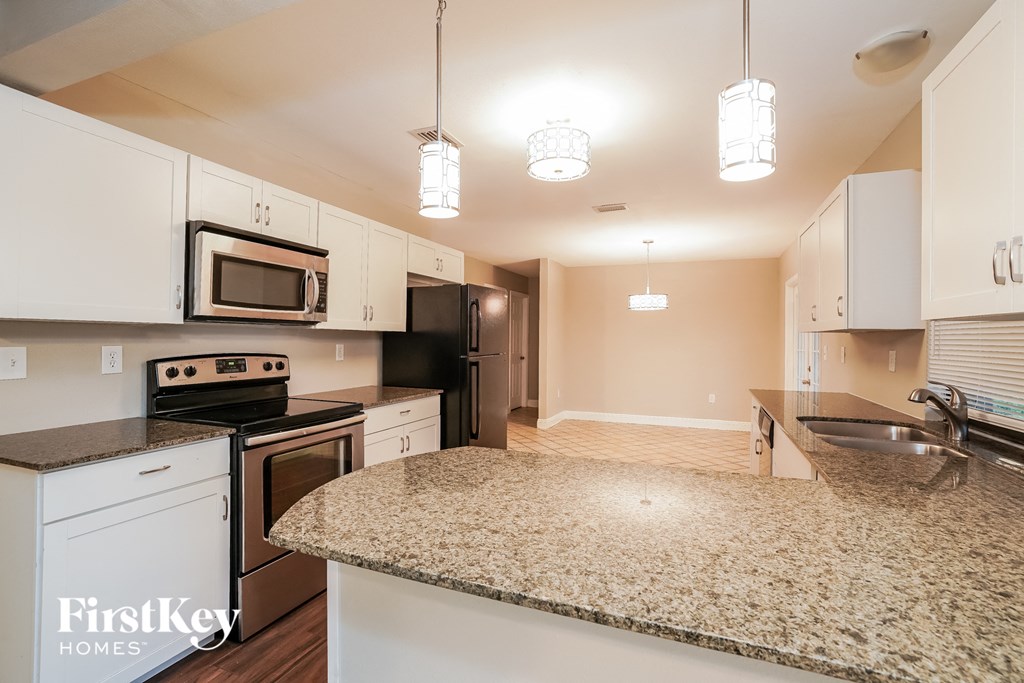 a kitchen with white cabinets and granite counter tops