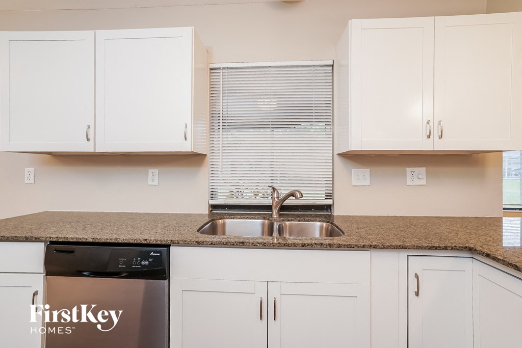 a kitchen with white cabinets and a granite counter top and a sink