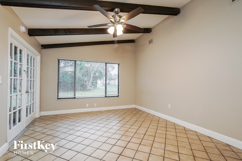 an empty living room with a ceiling fan and a window
