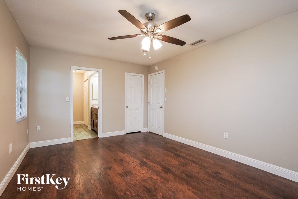 an empty living room with wood flooring and a ceiling fan