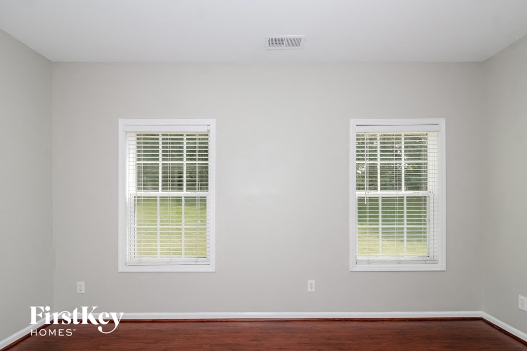 two windows in the corner of a room with wood floors