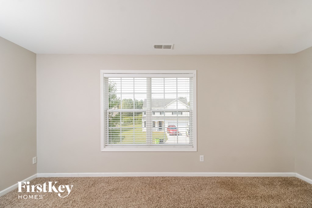 a living room with a window and a carpeted floor