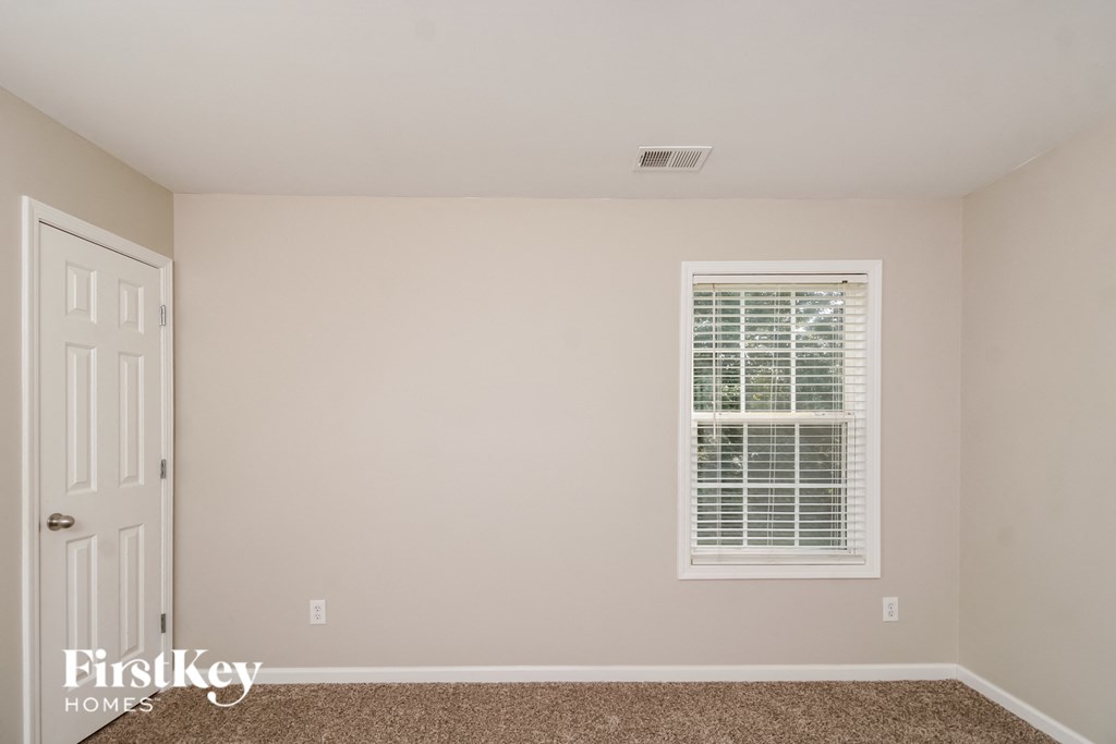 a bedroom with white walls and a window and a white door