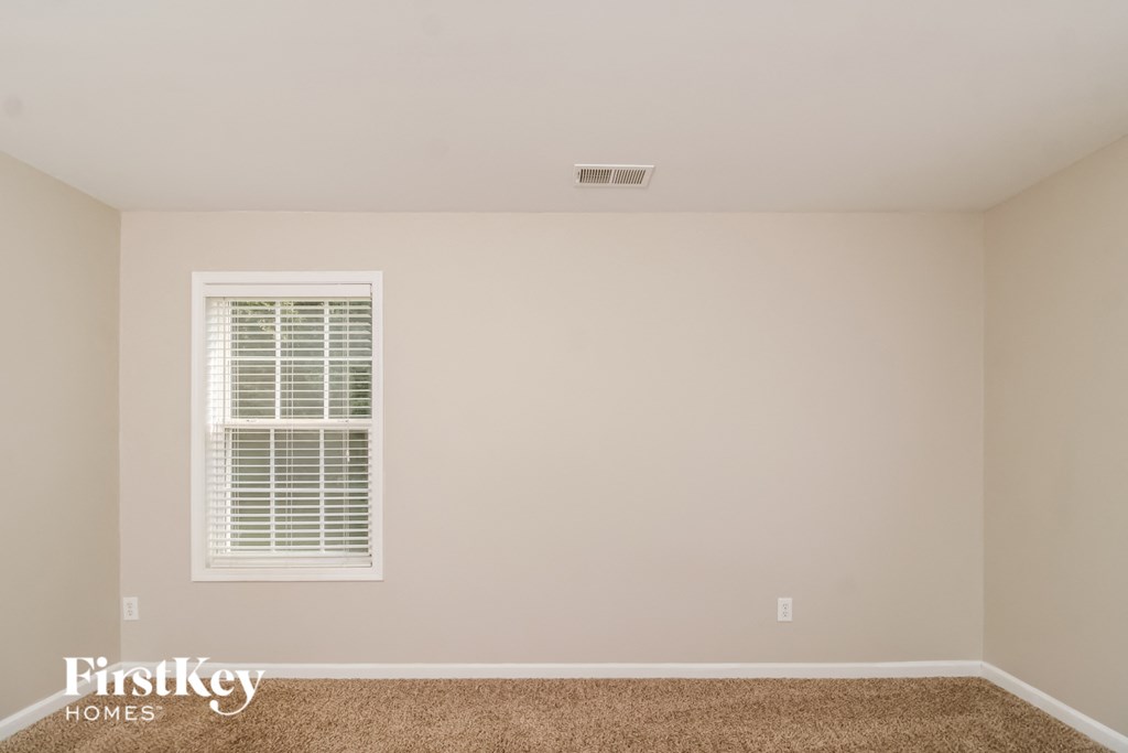 a bedroom with white walls and a window