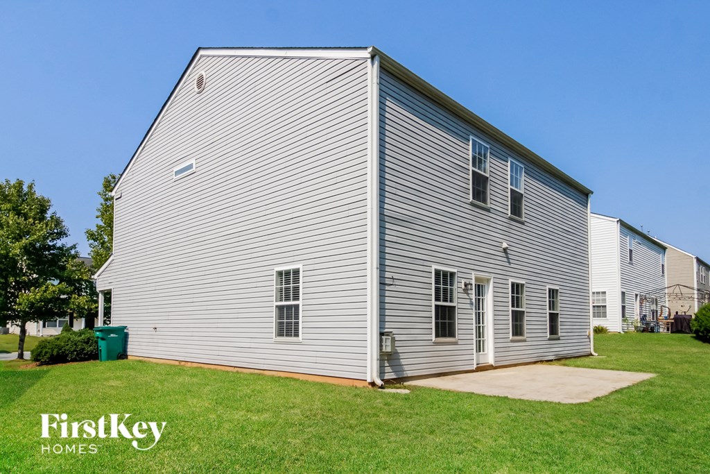a white house with gray siding and a green lawn