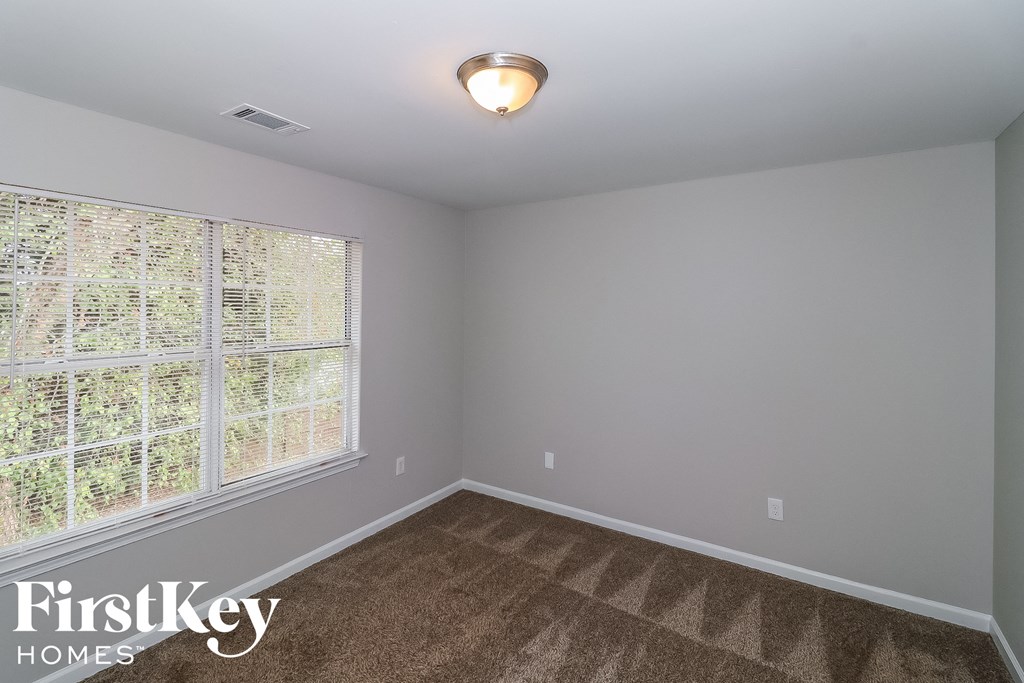 the second bedroom has a large window and carpeted flooring