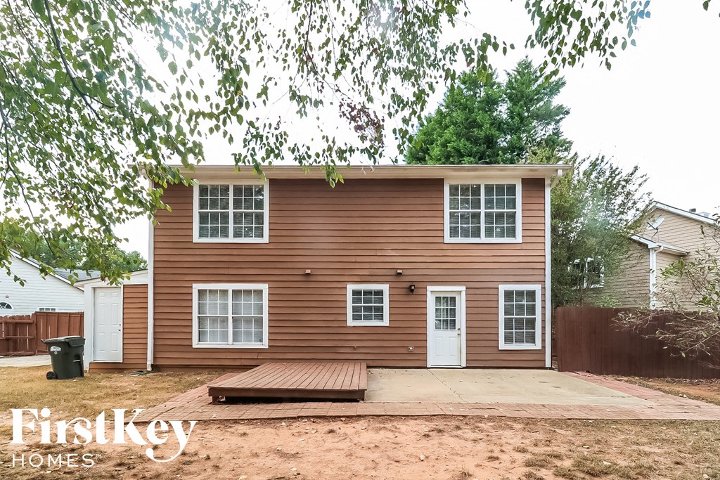 a small brown house with a deck and a sidewalk