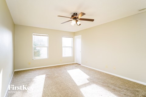 a living room with a ceiling fan and a carpet