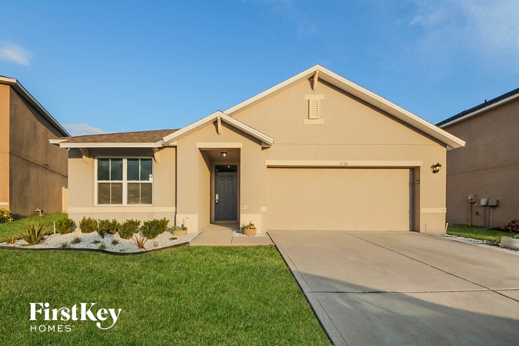 a beige house with a driveway and a garage door
