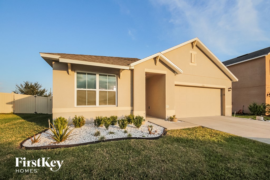 a beige house with a lawn and a driveway