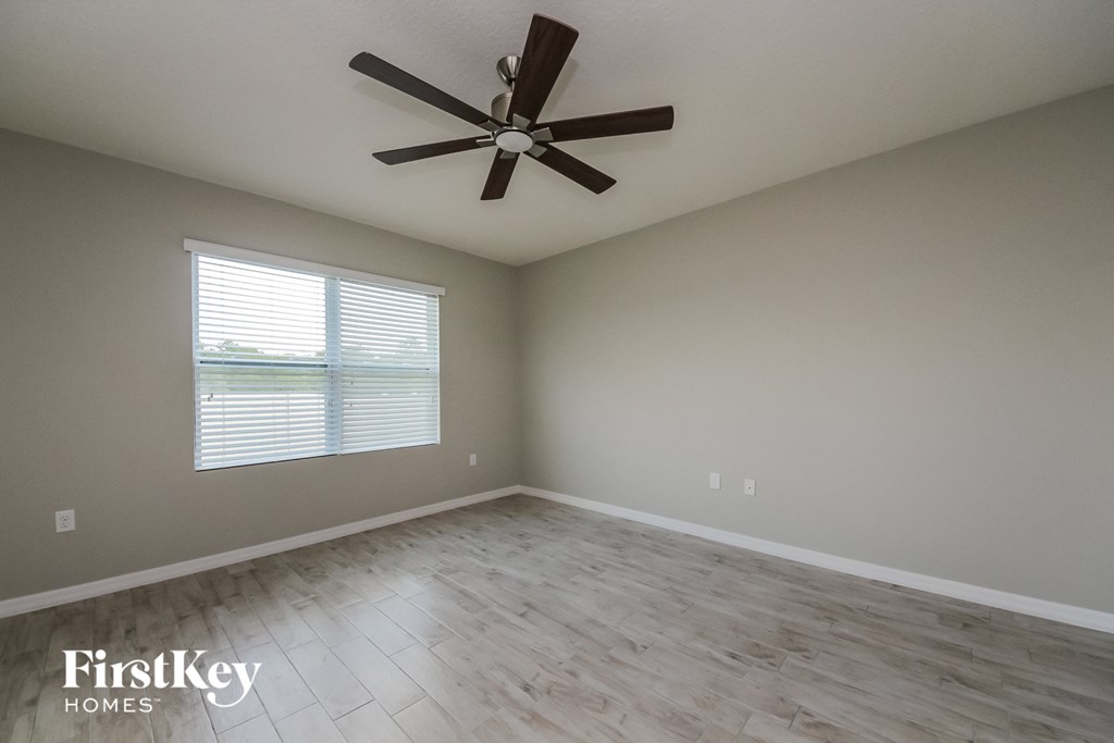 an empty living room with a ceiling fan and a window