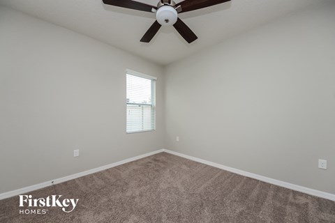 the spacious living room with carpet and ceiling fan
