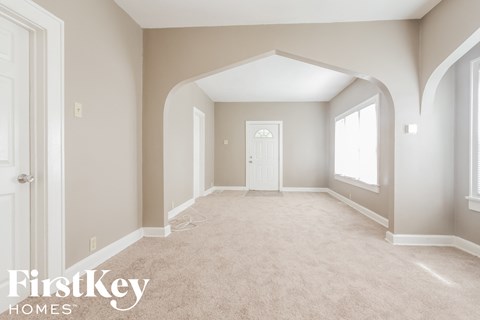 an empty living room with a white door and a carpeted floor
