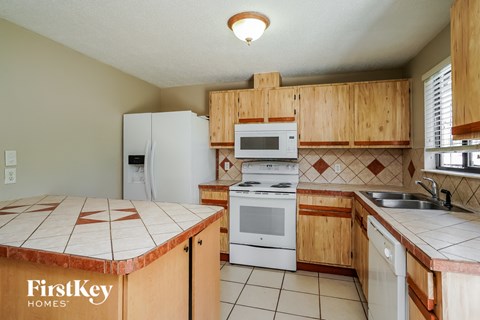 A kitchen with wooden cabinets and a tile counter top.