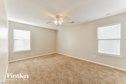 a bedroom with carpet and a ceiling fan and two windows